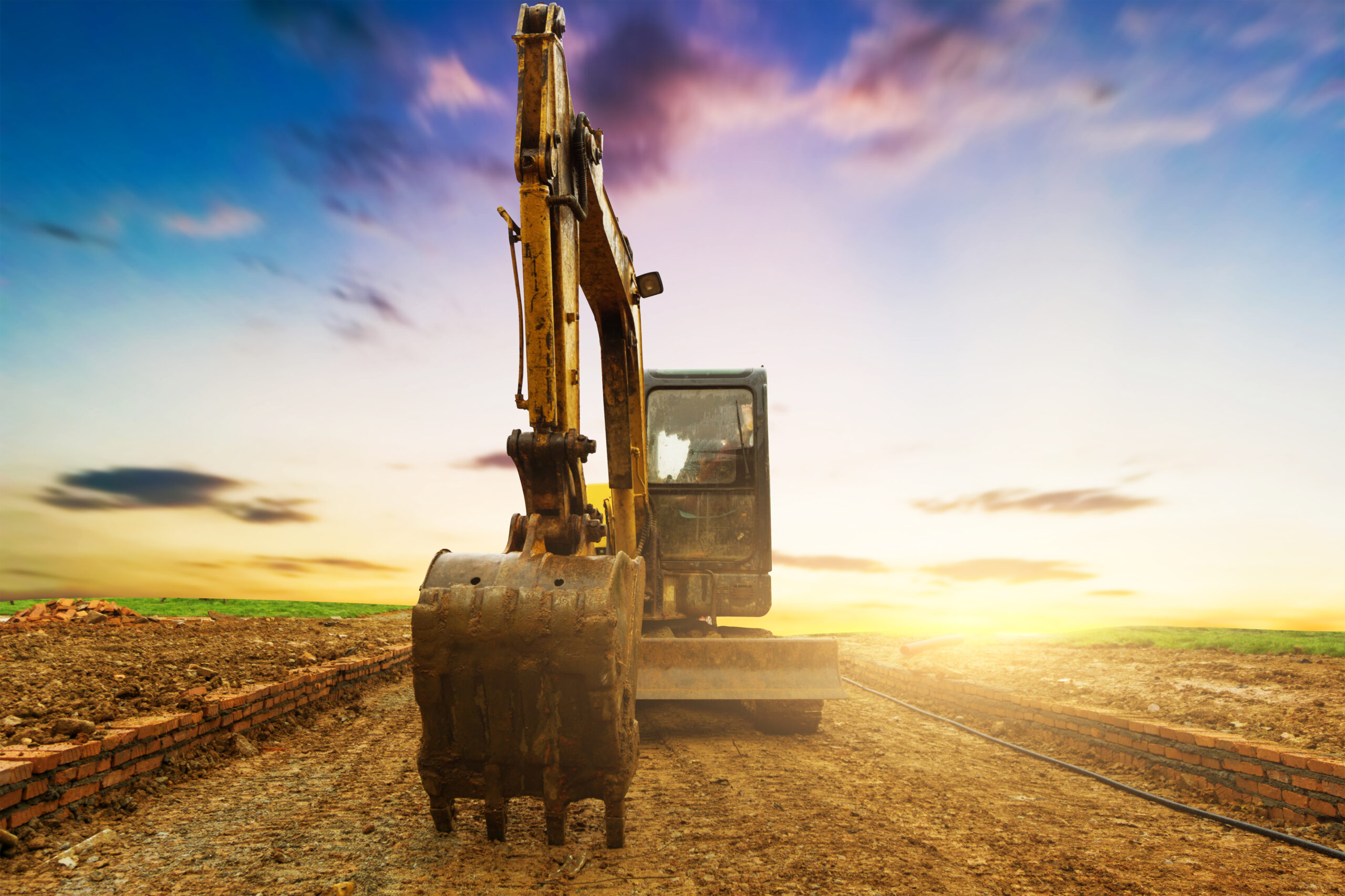 excavator in construction site on sunset sky background